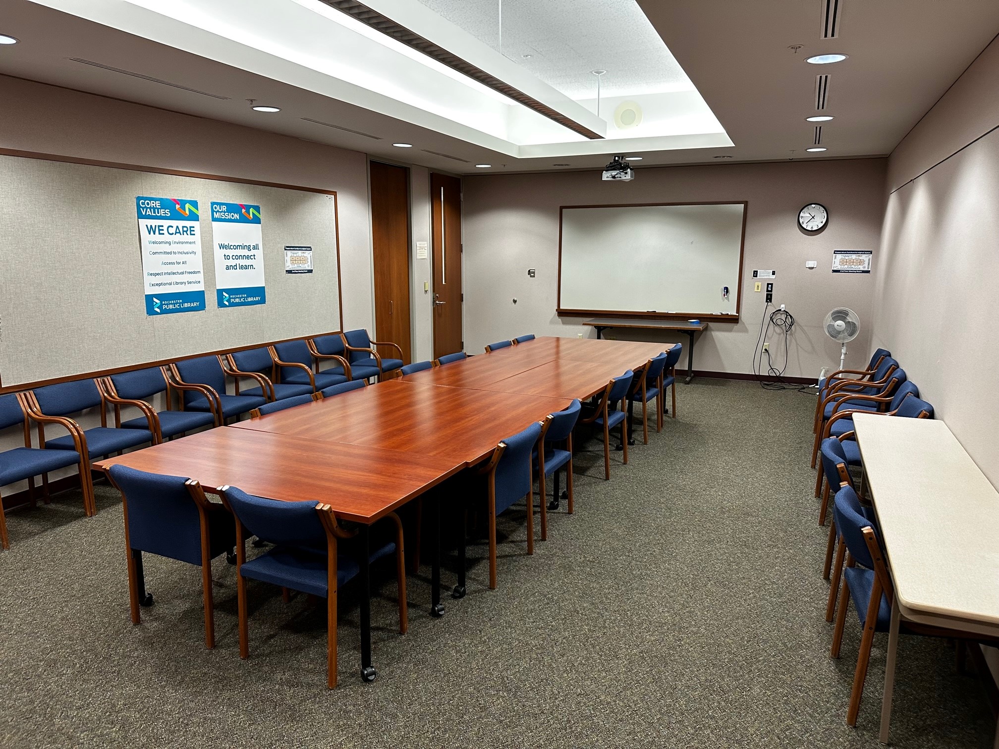 7 tables with chairs and a projector with white board