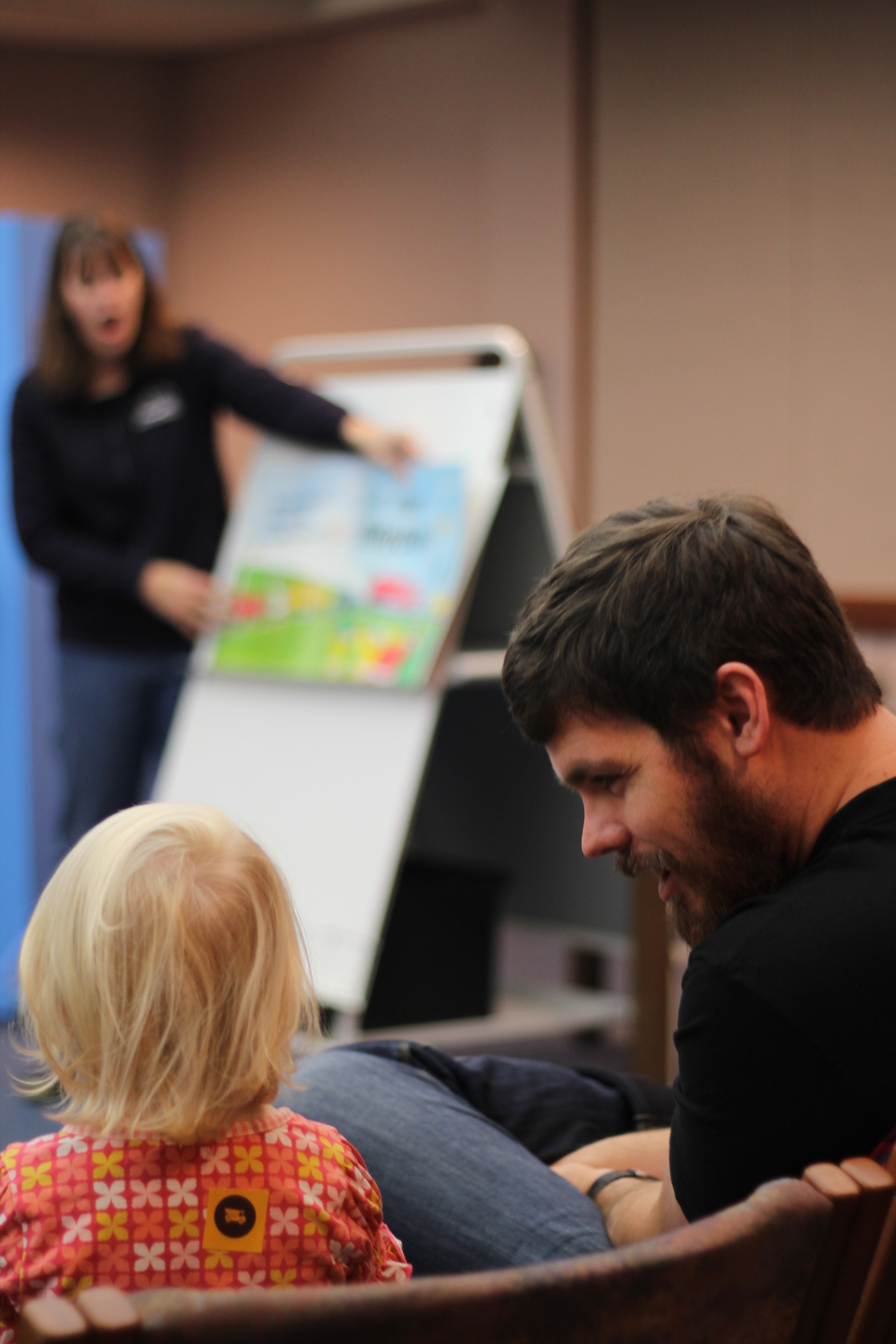 Adult and child interacting with storytime presenter in background