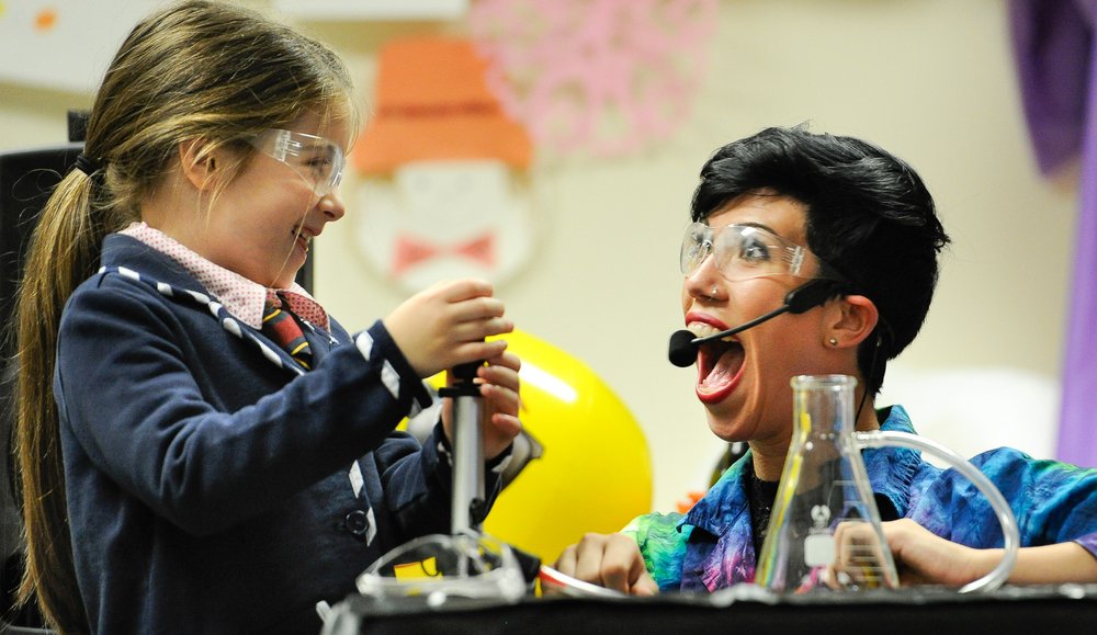 Performer and child conducting science experiment 