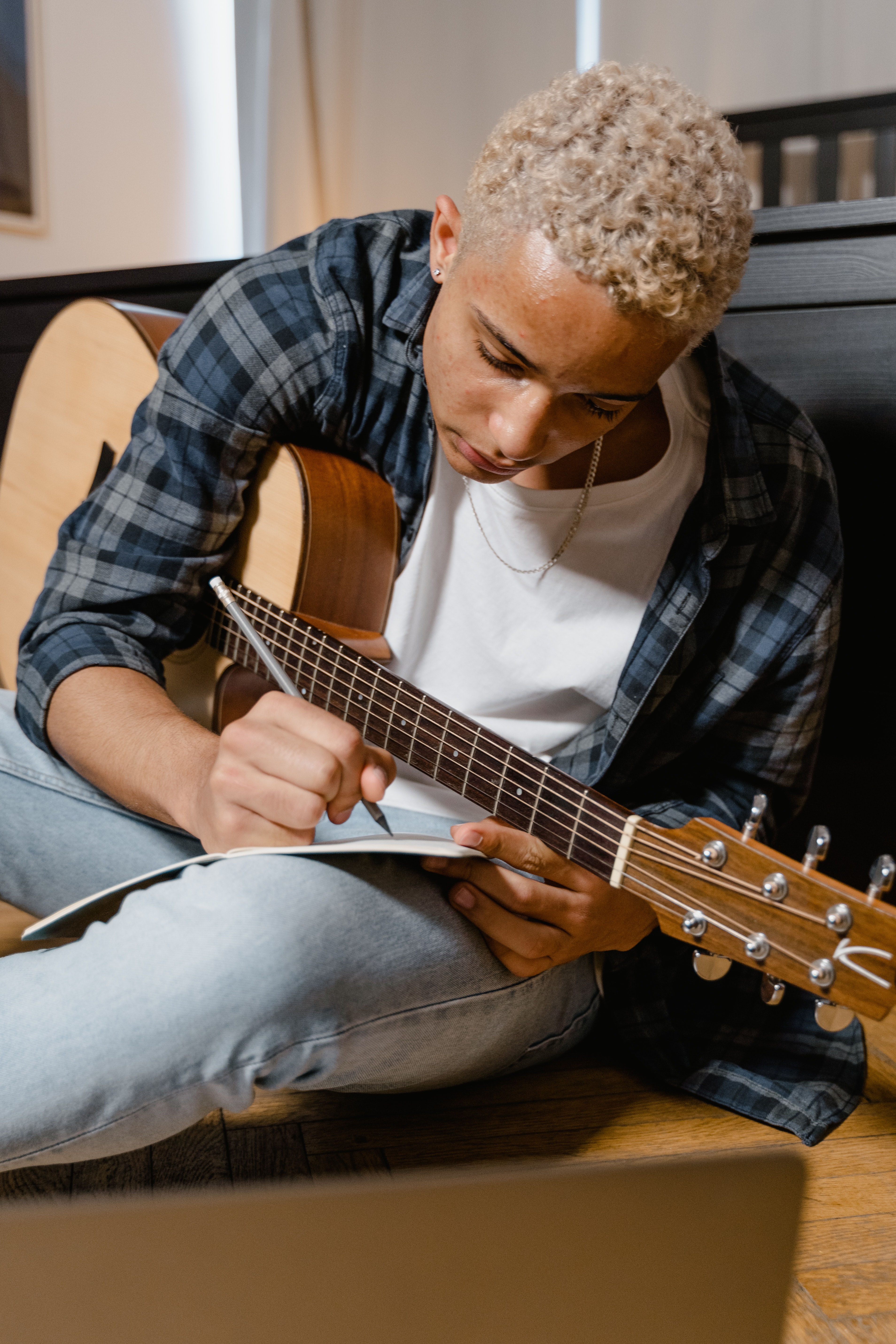 Person holding a guitar and writing music in a journal
