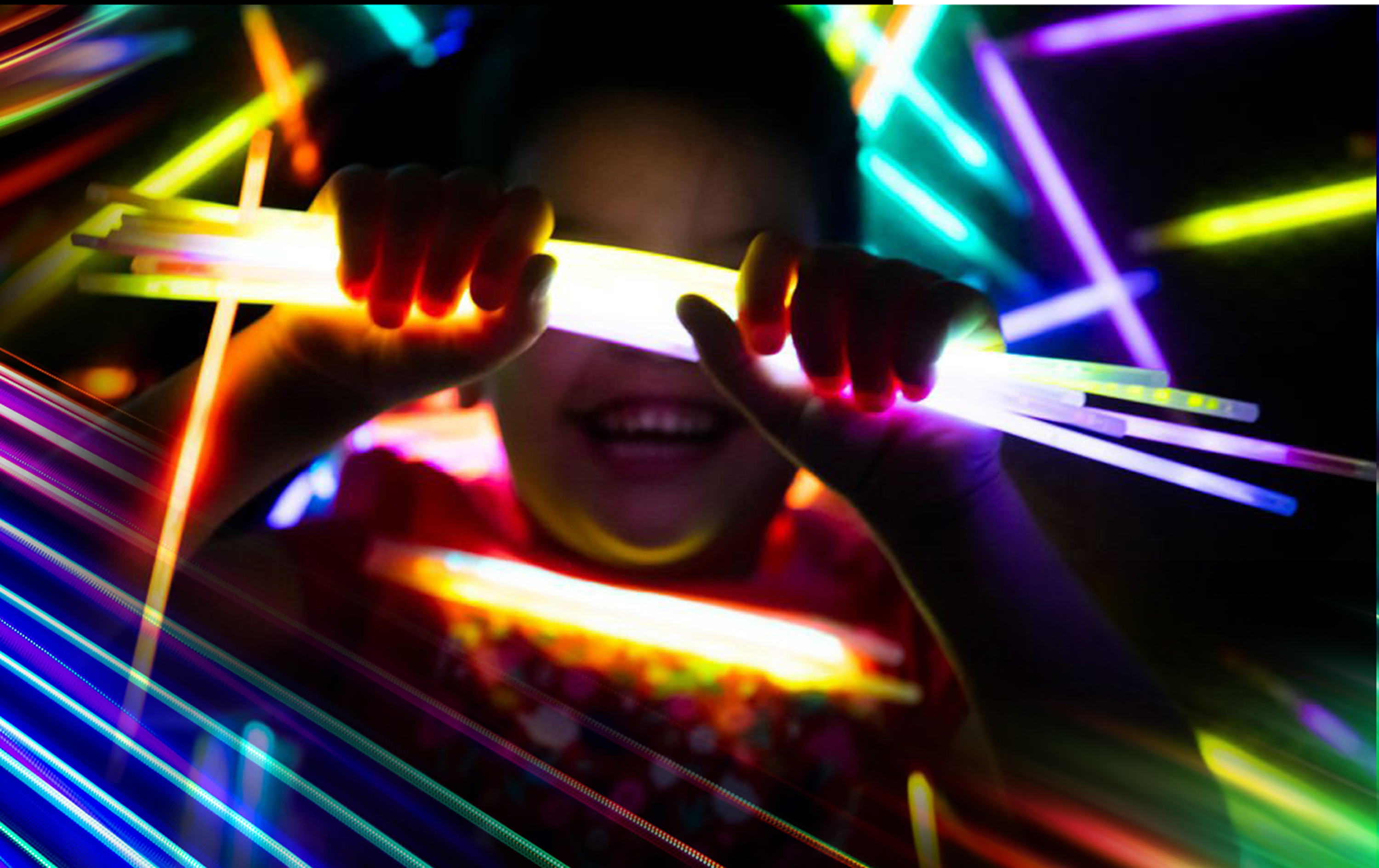child holding colorful glow sticks