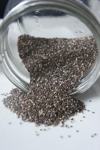 Tiny black and white seeds spilling out of a glass jar.