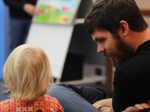 Adult and child interacting with storytime presenter in background