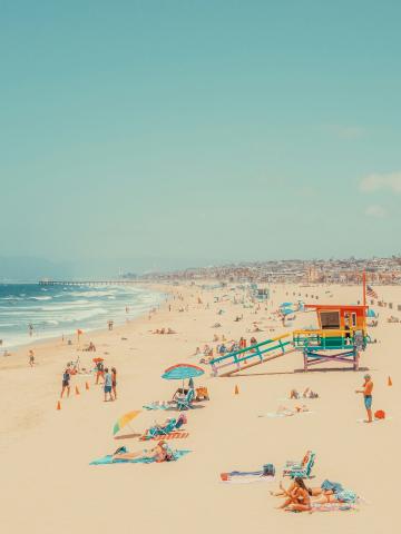 sunny day on Hermosa Beach, CA with colorful lifeguard stand and beach towels and umbrellas