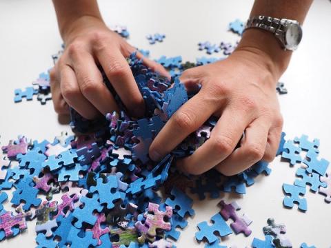 photo of two hands picking up puzzle pieces