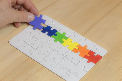 photo of hand picking up jigsaw puzzle piece