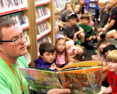 man reading book to children on bookmobile
