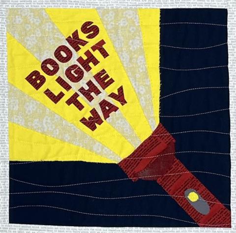 quilt block with an image of a flashlight and the words "Books light the way"