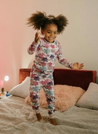 child in pajamas dancing on a bed