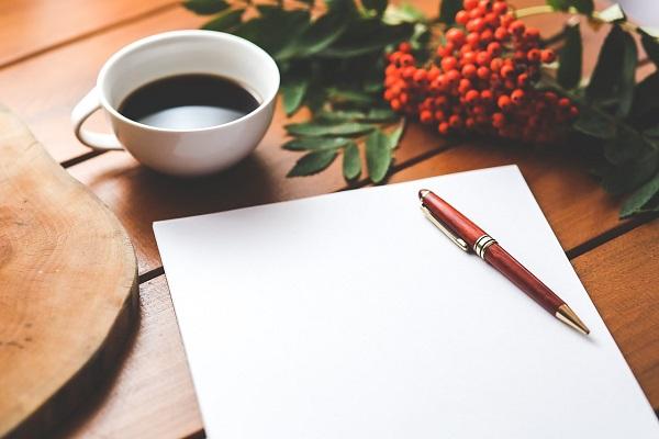 photo of table with paper, pen, flowers and tea cup on it.