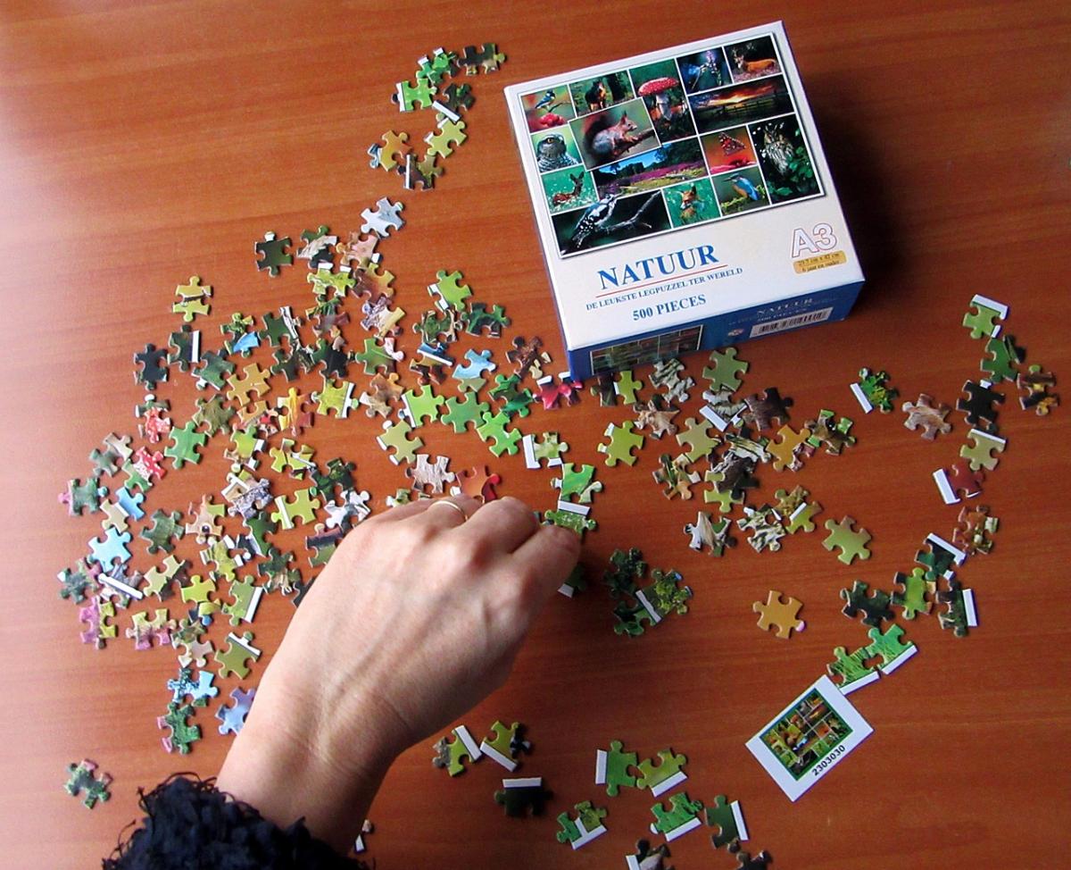 photo of hand putting together a jigsaw puzzle