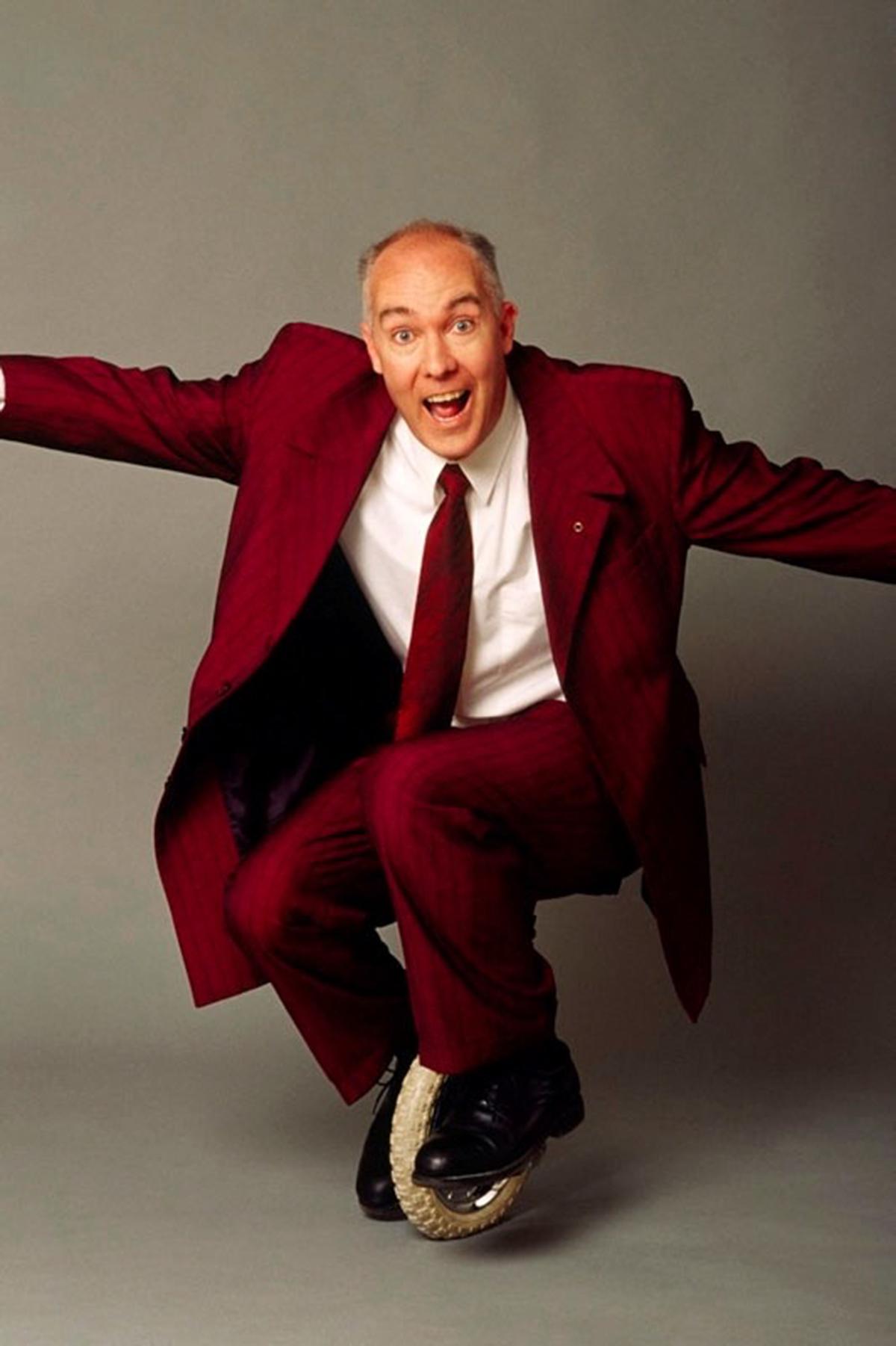 man in maroon suit on unicycle