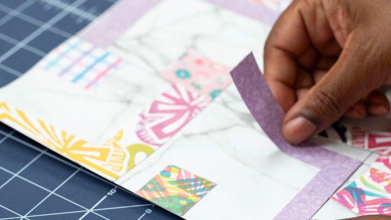 a person's hand is adding paper scraps to a collage